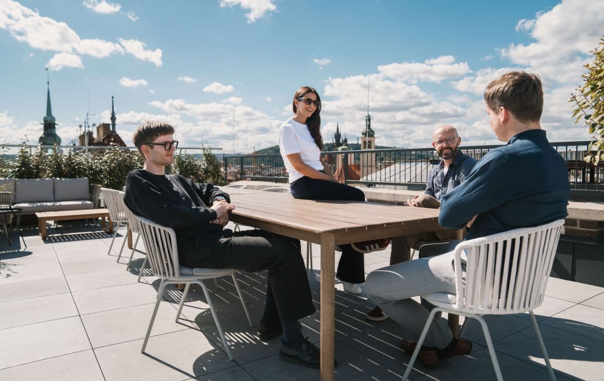 The Aspire11 team in conversation on a rooftop terrace above the Prague skyline